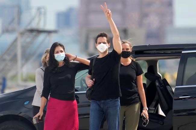 Michael Kovrig, centre right, waves to media as his wife Vina Nadjibulla, centre left, and sister Ariana Botha after his arrival at Pearson International Airport in Toronto on September 25, 2021. THE CANADIAN PRESS/Frank Gunn
