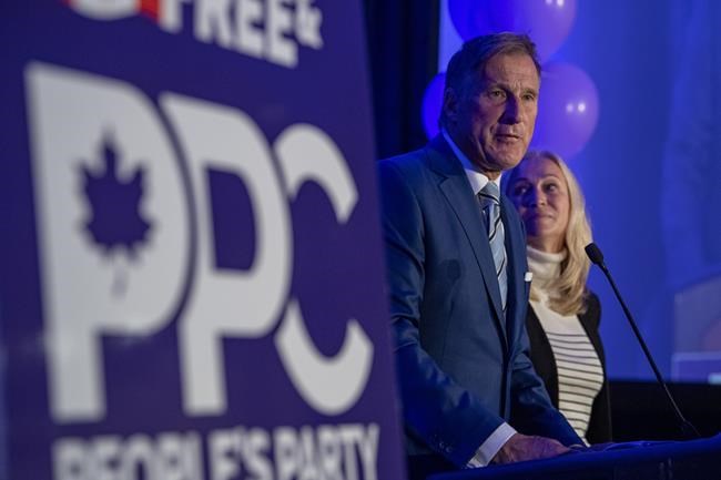 People's Party of Canada Leader Maxime Bernier and wife Catherine Letarte speaks from a podium to supporters during the PPC headquarters election night event in Saskatoon, Sask., Monday, Sept. 20, 2021. THE CANADIAN PRESS/Liam Richards