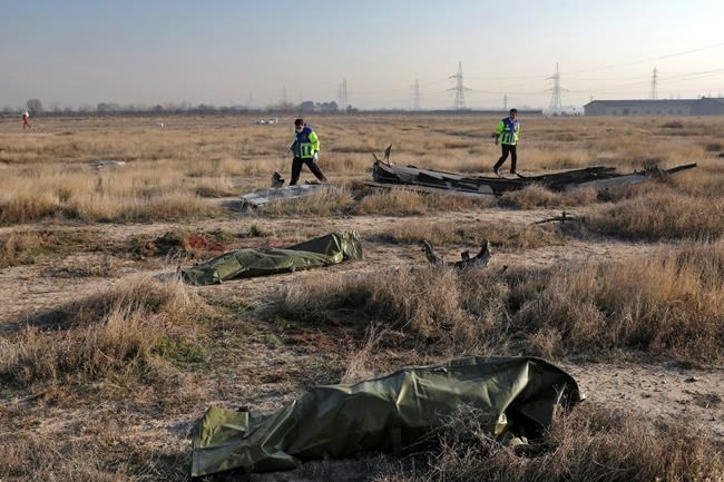 Rescue workers search the scene where a Ukrainian plane crashed as the bodies of victims in body bags lie on the ground, in Shahedshahr, southwest of the capital Tehran, Iran, Wednesday, Jan. 8, 2020. A Ukrainian airplane with more than 170 people crashed on Wednesday shortly after takeoff from Tehran's main airport, killing all onboard. (AP Photo/Ebrahim Noroozi)