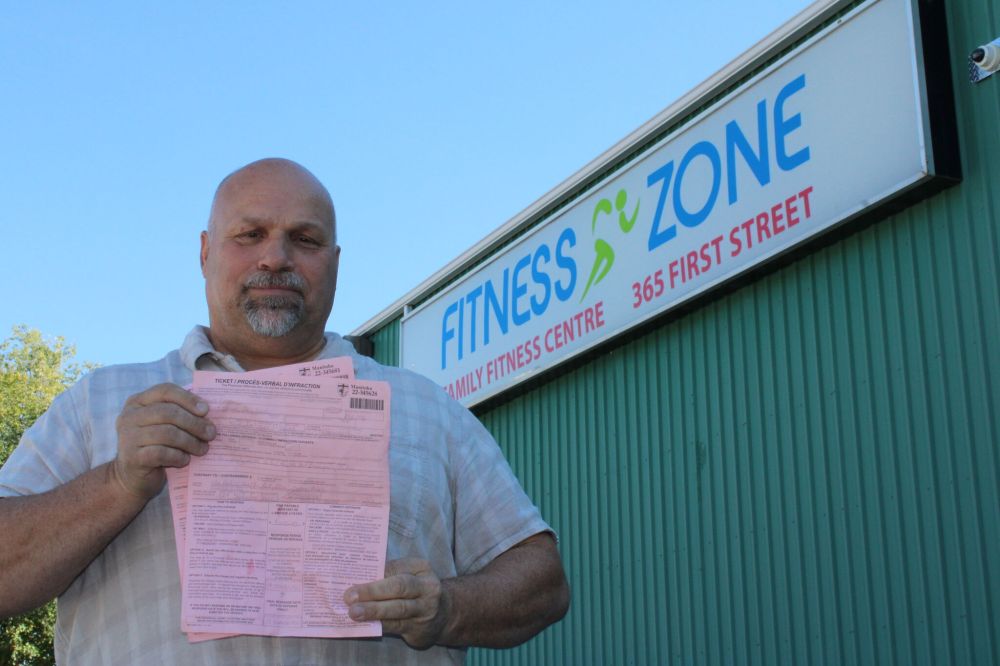 GREG VANDERMEULEN / THE CARILLON
Fitness Zone owner Les Spence holds a pair of $5,000 tickets he received for failing to comply with a public health order.