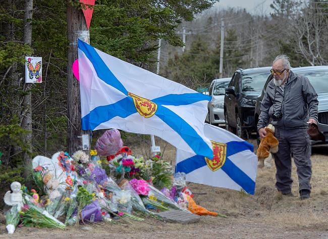 A man pays his respects at a roadside memorial in Portapique, N.S. on Thursday, April 23, 2020. RCMP say at least 22 people are dead after a man who at one point wore a police uniform and drove a mock-up cruiser, went on a murder rampage in Portapique and several other Nova Scotia communities. THE CANADIAN PRESS/Andrew Vaughan