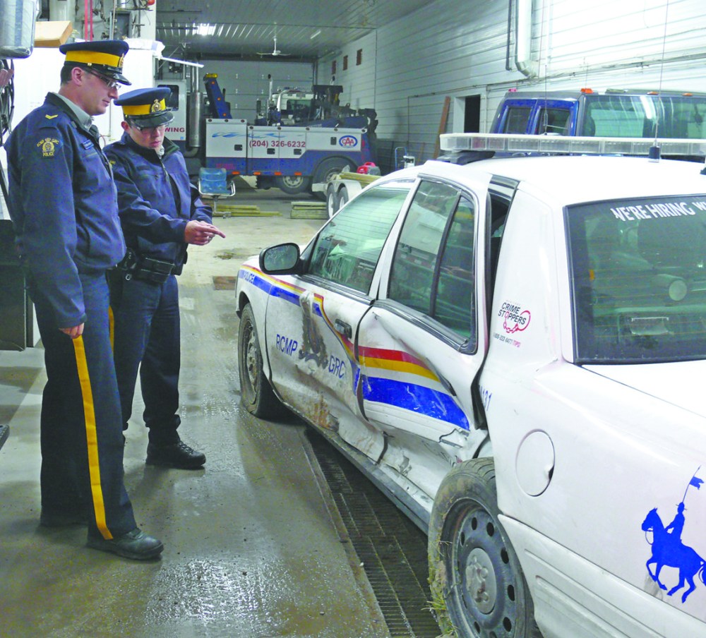 JUDY PETERS | THE CARILLON ARCHIVES
Steinbach RCMP Cpl. Kyle McFadyen and Cst. Rob French inspect their cruiser at Steinbach Towing a day after a drunk driver ran into them. There were no serious injuries.