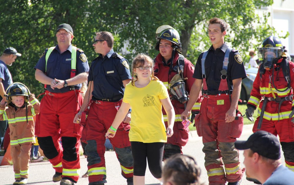 IAN FROESE | THE CARILLON ARCHIVES
Members of the Kleefeld Fire Department, including two young supporters, take part in the parade at last year's Kleefeld Honey Festival.