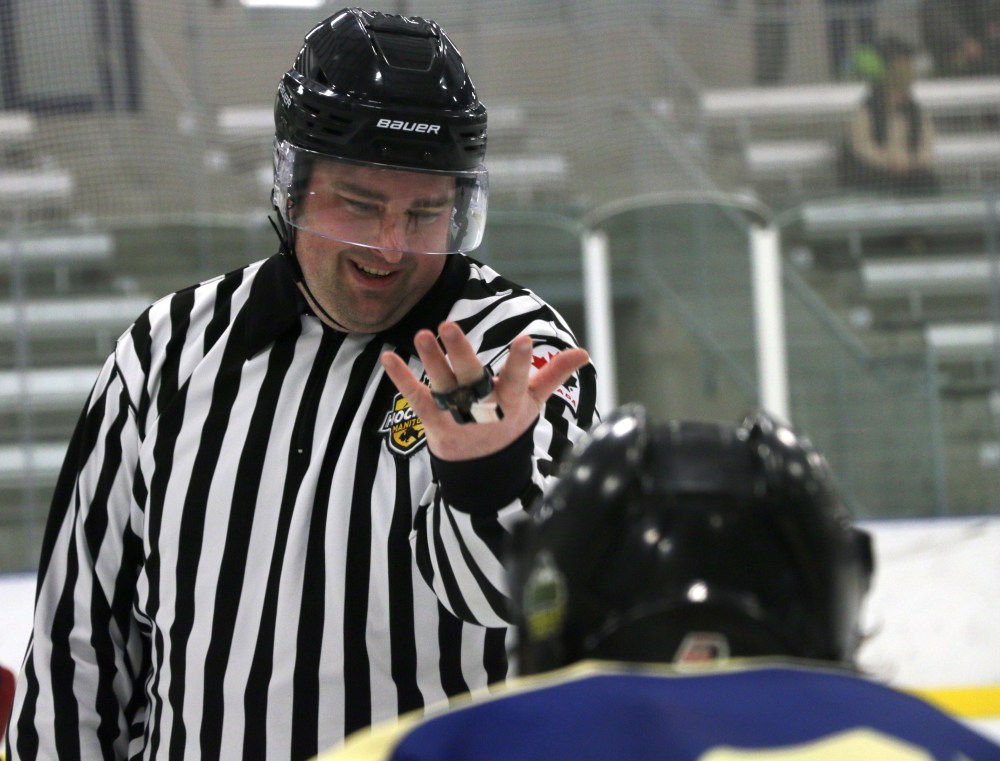 A linesman laughs as he gestures to two wingers to back up out of the faceoff circle during a HTJHL playoff game Feb. 8. (Cassidy Dankochik The Carillon)