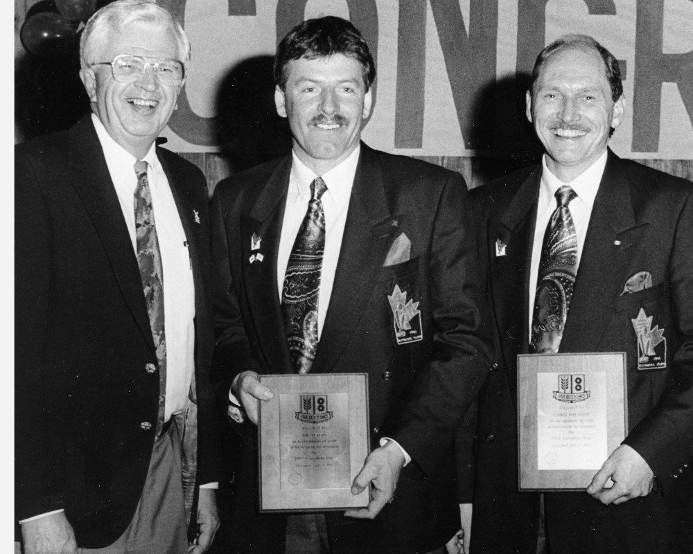 Wes Reimer presents Town of Steinbach plaques to 1992 Brier champions Vic Peters and Chris Neufeld at a Steinbach Curling Club banquet in their honour.