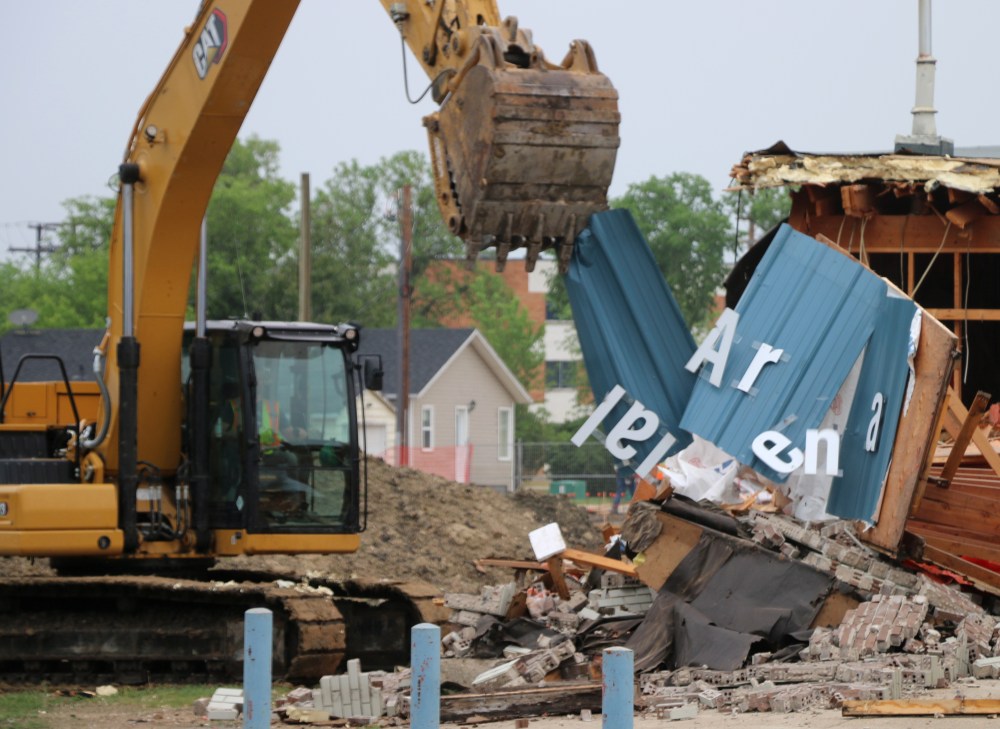 A backhoe operator tears into the Centennial Arena sign, sending the letters flying. (Cassidy Dankochik The Carillon)