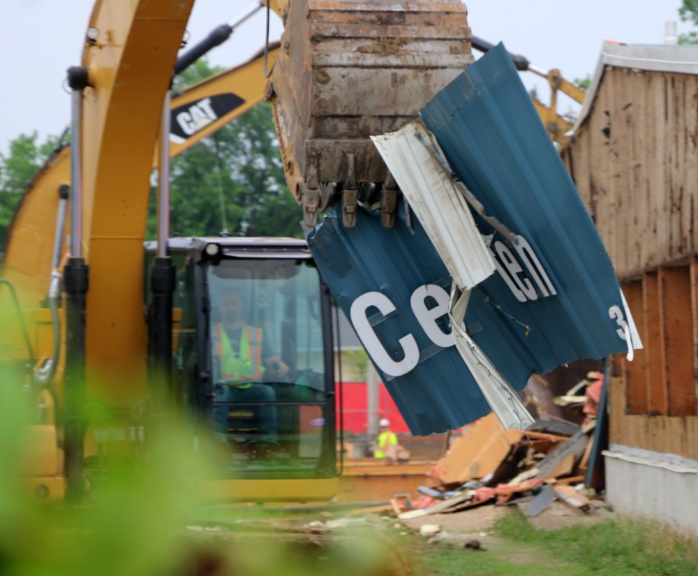 A backhoe operator tears into the Centennial Arena sign, sending the letters flying. (Cassidy Dankochik The Carillon)