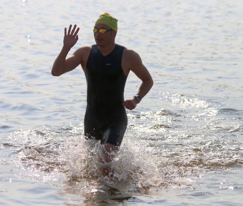 A competitor waves to the fans as he completes a lap of the swimming course. (Cassidy Dankochik The Carillon)