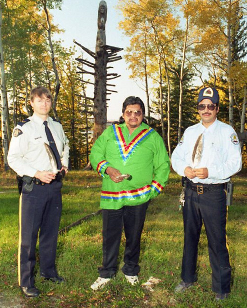 CARILLON ARCHIVE
With a totem pole looming in the background, RCMP Constable Gerry Thomas, Justice Committee leader Baptiste Caribou and Band Constable Bill Green each hold an eagle feather symbolizing co-operation among the three law enforcement entities at Pukatawagan.