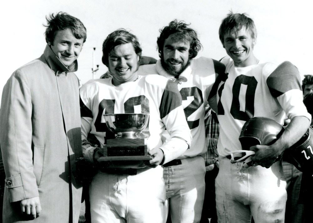 Dr. Henry Janzen, former Winnipeg Blue Bomber great, presents the Henry Janzen Cup to Landmark Dutchmen captains Gordon Reimer, Allan Reimer and Leonard Goertzen, after Landmark’s victory over the Steinbach Wheelers in the 1975 Rural Manitoba Intermediate Nine-Man Football League championship game.