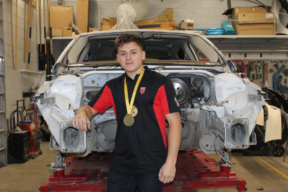 Chris Gareau The Carillon
James Bartel with the car he is practising on in the Steinbach Regional Secondary School shop, wearing his provincial and national medals and his Team Canada shirt. The Grade 12 student won the Skills Canada competition and is off to Lyon, France with teacher Jessy Unrau to compete in Autobody Repair against the world's best high school and college students.