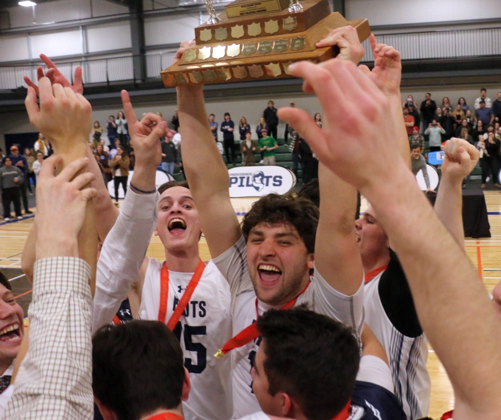 Avery Bergman shouts with glee as he carries the Manitoba Colleges Athletic Association men's volleyball championship trophy back to his teammates after being presented it. (Cassidy Dankochik The Carillon)