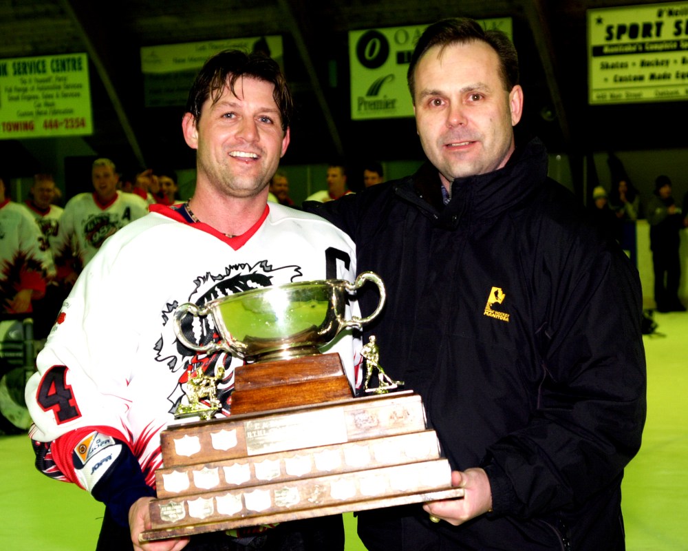 Hanover Tache Hockey League president Doug Maughan presents the L.A. Barkman Memorial Trophy to Springfield 96’s captain Grant Sellen, who led all scorers with 15 goals and 17 assists in eight games during the playoffs, to cap off the 2004-05 season in March.
