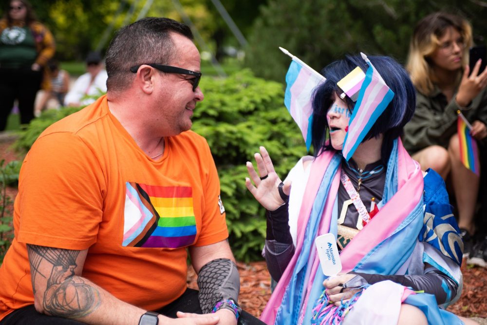 SVJETLANA MLINAREVIC THE CARILLON
NDP MLA Logan Oxenham smiles while Hayden Lessard speaks to him during Steinbach Pride on June 23, 2024, at K.R. Barkman Park. Oxenham is Canada's first transgender MLA to win a seat in the legislature. In early June, he introduced a bill commemorating transgender and two-spirit people, which passed.
