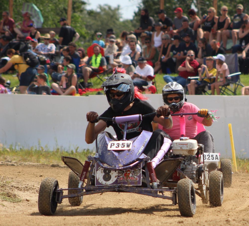 CHRIS GAREAU THE CARILLON
The driver for Spark Plug Cup winner and hometown team Moonshadow Hogs tries to overtake the driver for El Diablo during their 100-lap second heat in front of a large crowd on a hot day at the 15th St Labre 200.