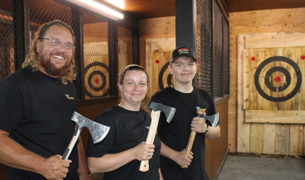 GREG VANDERMEULEN THE CARILLON
Colin and Jennie Williams stand with their son Zakery in front of some of the axe throwing lanes in their facility.
