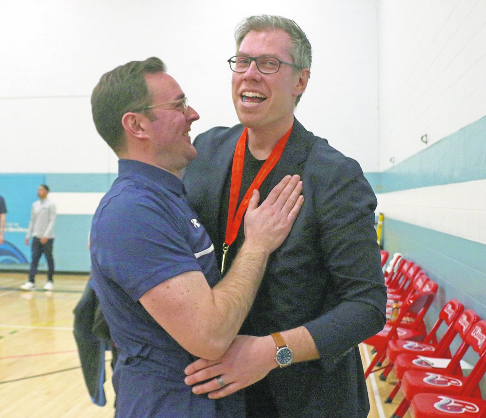 Providence women's basketeball head coach Joel Coursey (right) is congratulated by men's coach Pierre Dubreuil after winning his first Manitoba Colleges Athletic Conference championship. (Cassidy Dankochik The Carillon)