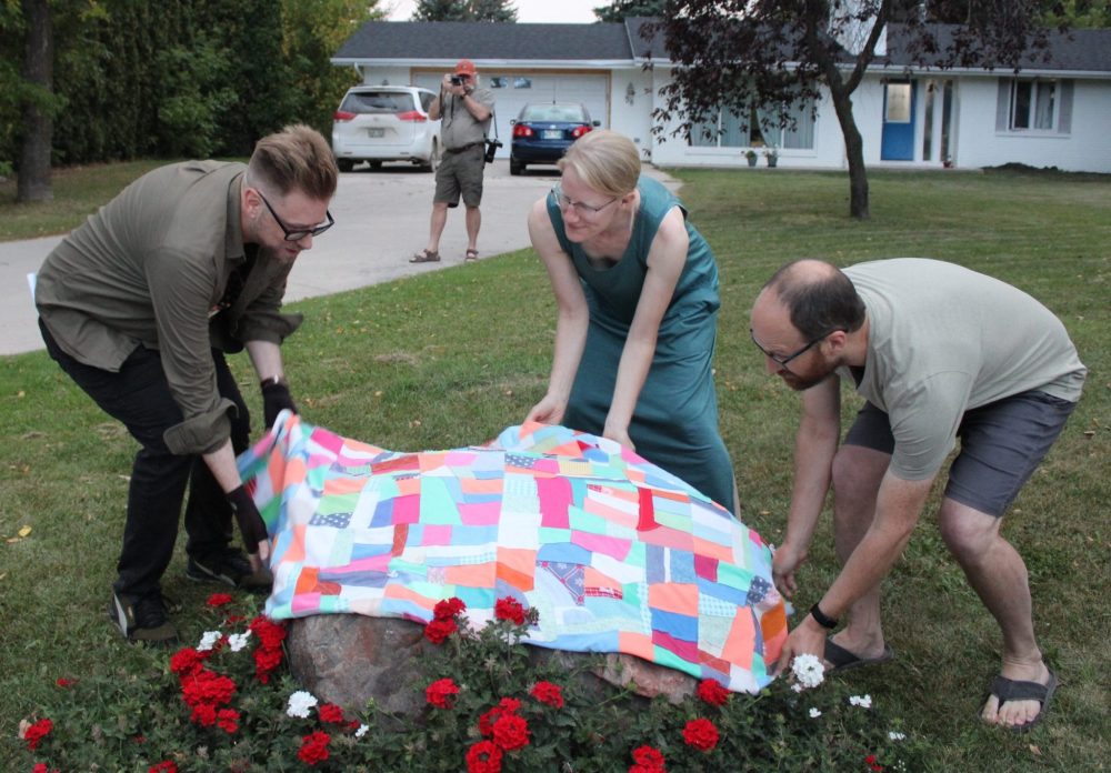 GREG VANDERMEULEN THE CARILLON
Andrew Unger and homeowners Kara and Jeremy Hawbaker remove the quilt covering the plaque in front of the teenage home of Miriam Toews.