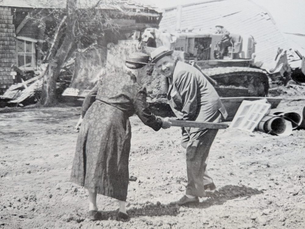 George Wright, Steinbach: Is There Any Place Like It?
A. D. Penner gets spanked by his mother for demolishing the last remaining housebarn in Steinbach in this staged photo from 1960. This housebarn was built by the Friesens but later owned by the Kornelsen family. The house was cleared for a car storage lot at the corner of Highways 12 & 52, what is now the site of Victoria Plaza.
