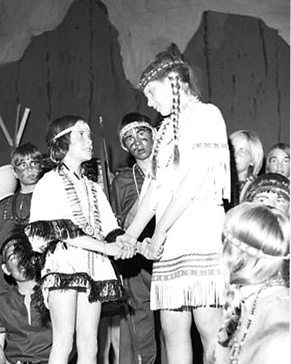 CARILLON ARCHIVES
The instigator of the plan to have Dawn Boy walk to the top of the mountain to speak to the rain god is Storm Dancer (center right, played by Marlyce Toews). Here, she sadly tells Dawn Boy’s little Indian maiden, Silver Dew (Joy Gatten), that she has little hope of his ever coming back.
