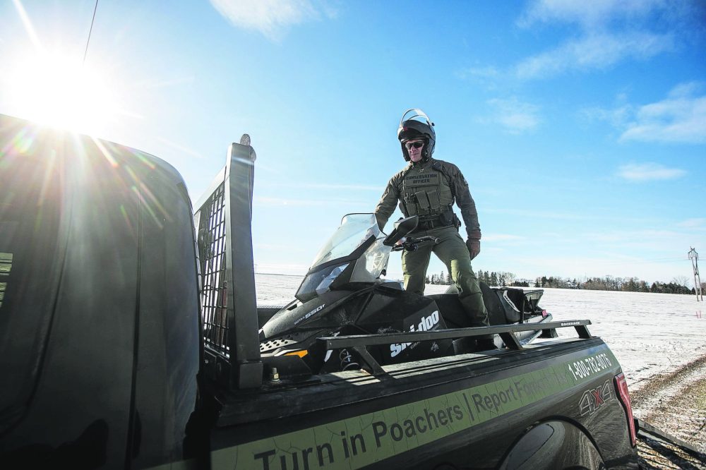 MIKAELA MACKENZIE WINNIPEG FREE PRESS
Conservation officer Nick Woroniuk drives a snowmobile back onto the conservation truck after a press conference close to the Canada-US border west of Emerson on Monday, Jan. 27, 2025.