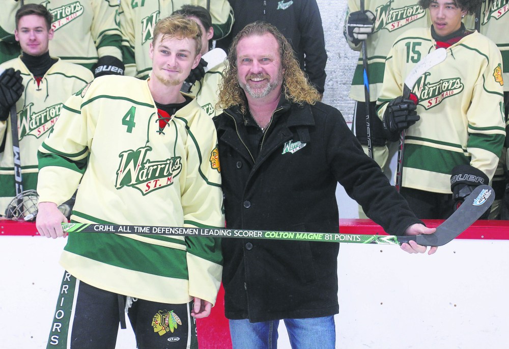 Colton Magne is presented with a stick marking his achievement as the Capital Region Junior Hockey League's all-time points leader for defensemen by St Malo Warriors president Ken Hassan. (Cassidy Dankochik The Carillon)