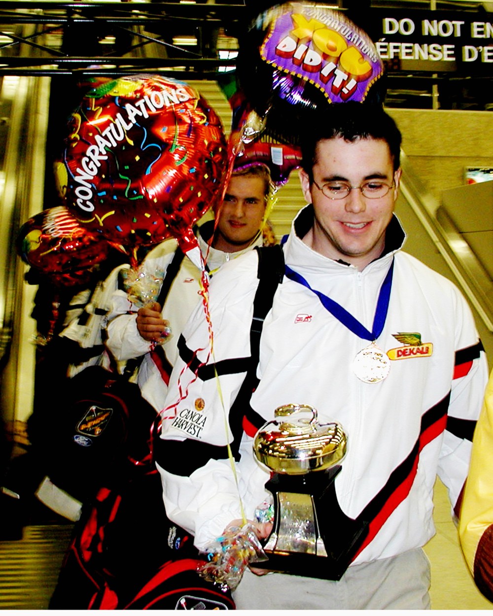 Clutching the silverware, world curling championship skip David Hamblin is followed by third Ross Derksen to arrive at a victory celebration at Winnipeg International Airport.