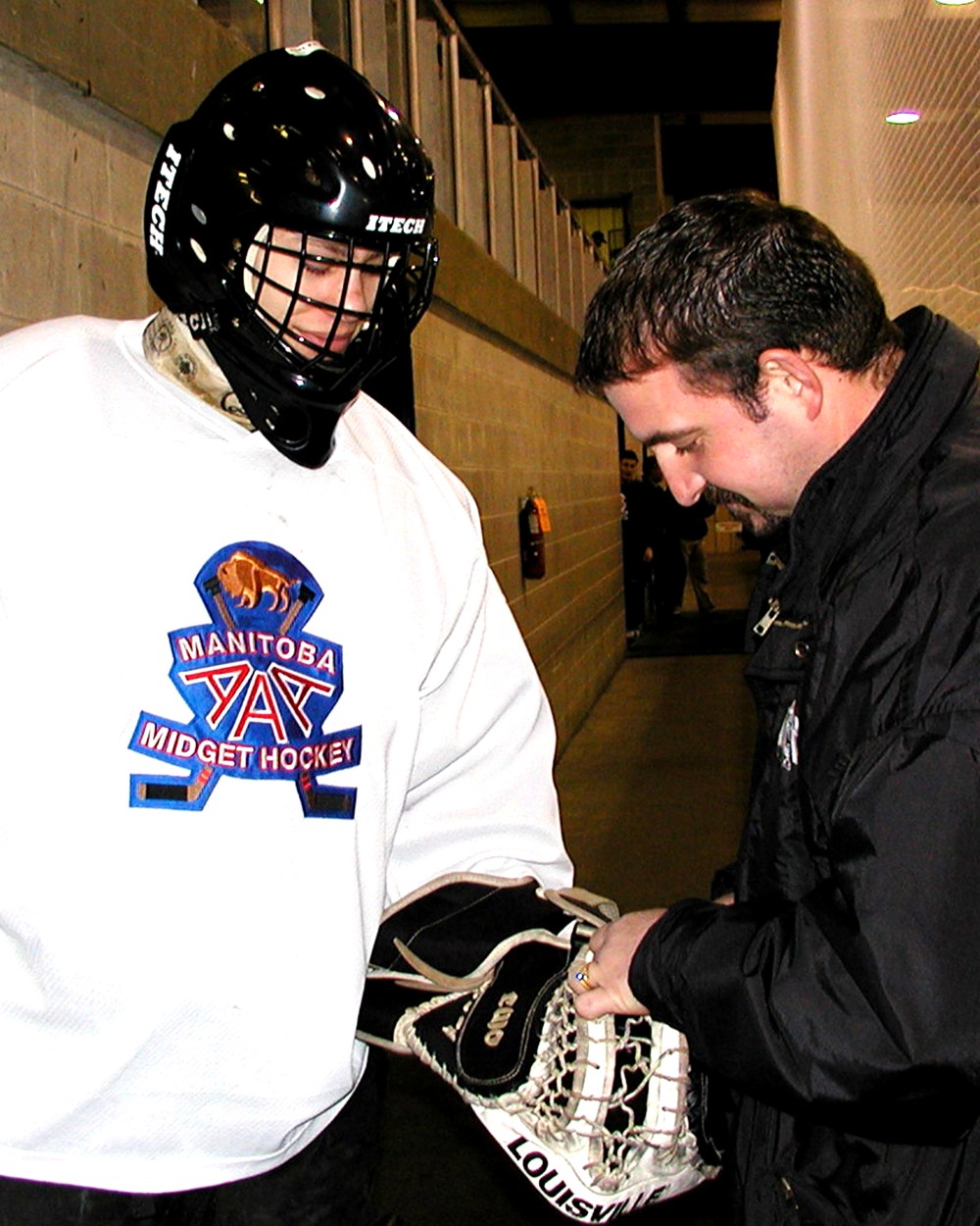 Team East bench coach Ivan Koop checks Matt Neufeld’s equipment prior to goaltender’s taking his turn in the nets during the 2002 Manitoba ‘AAA’ Midget Hockey League all-star game. Neufeld shut out the West for the third period and overtime in his team’s 6-5 win.