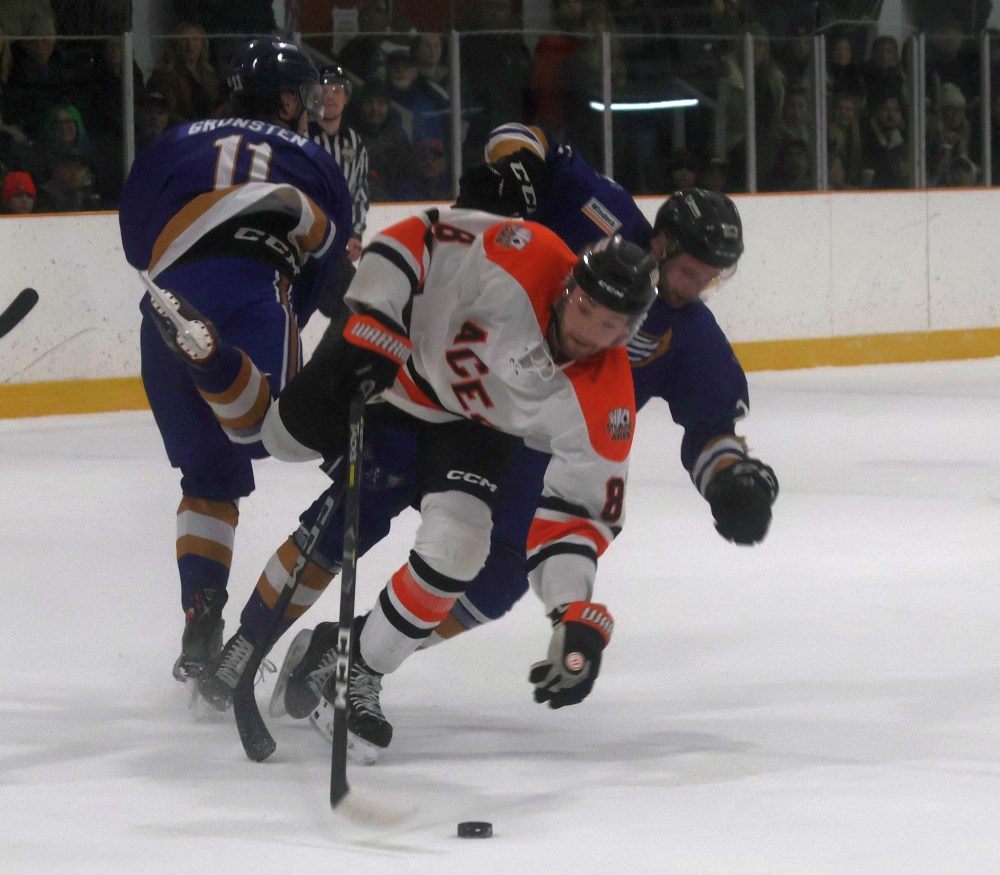 Caleb Paisley crashes through two Springfield defenders during game seven of the SEMHL finals. (Cassidy Dankochik The Carillon)