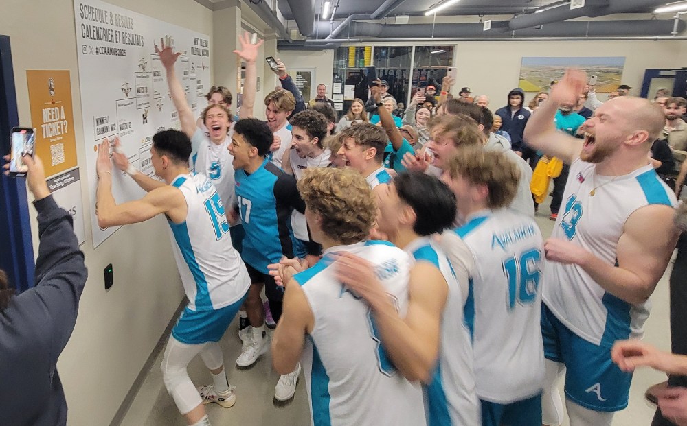 The College of the Rockies, featuring Ile des Chenes' Reece Clarke (number 17 in blue) and SRSS provincial champion Boston Thiessen celebrate winning the bronze medal at the CCAA National Championships in Niverville by placing their logo on the standings board. (Cassidy Dankochik The Carillon)