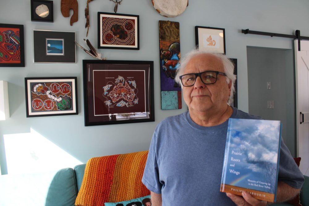 GREG VANDERMEULEN THE CARILLON
Philippe Sabourin holds his new book, Prairie Roots and Wings, in front of some of the memories of his travels.