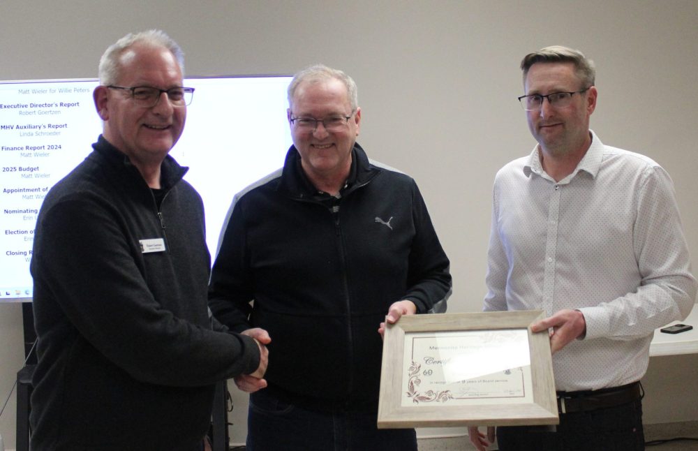 Create...
By Chris Gareau
CHRIS GAREAU THE CARILLON
Waldy Ens (centre) is recognized by executive director Robert Goertzen and board president Matt Wieler for serving nine years on the Mennonite Heritage Village (MHV) board. His three terms of three years each is the most anyone can serve. Ens said his service on the board and as secretary was in honour of his father Gerhard Ens, who served as president and secretary on the board before him, was a founding member of the Mennonite Historical Society that established the MHV, and for whom the gallery is named after.