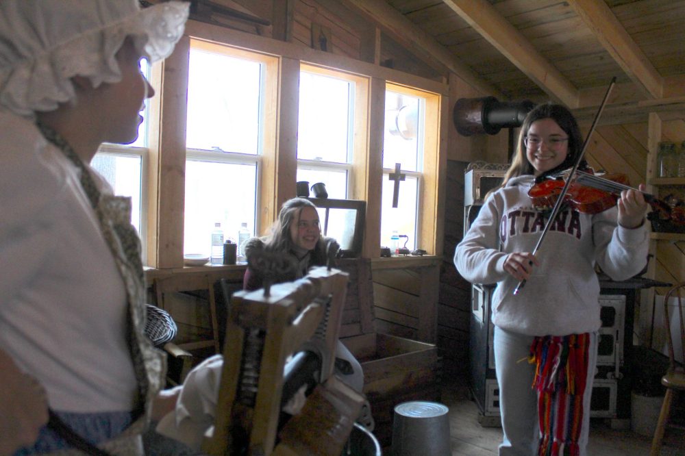 CHRIS GAREAU THE CARILLON
Milaine Fillion (left) keeps clothes clean the old-fashioned way as Julie Fillion fiddles during the Sugaring Off Festival in St Pierre.