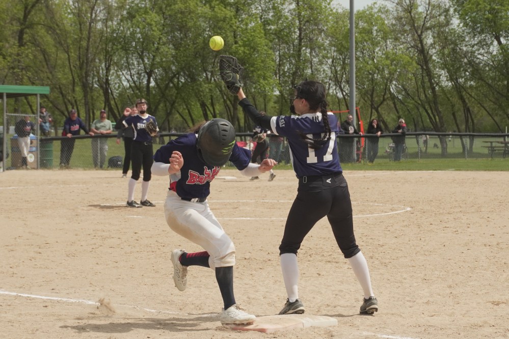 Gracie Enns (front right) reaches for the ball to get the Braves’ batter out at first base on Wednesday, May 21. TONI DE GUZMAN THE CARILLON
