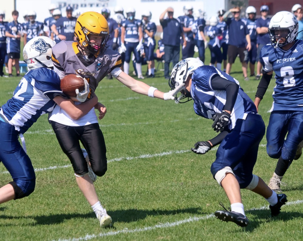 An SRSS junior varsity player looks to shake off a pair of Grant Park tacklers. (Cassidy Dankochik The Carillon)