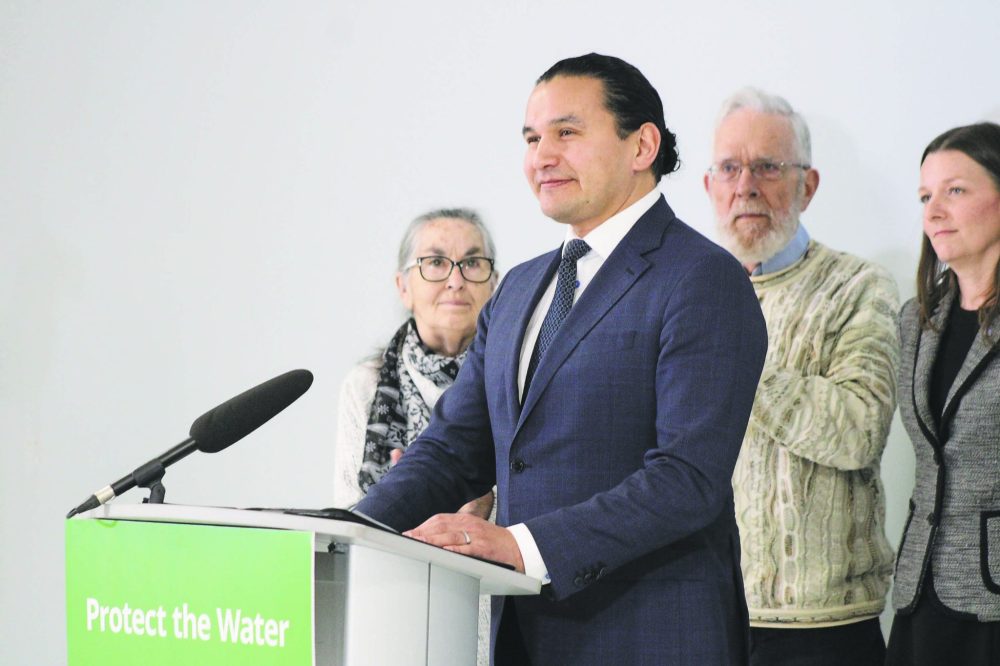 GREG VANDERMEULEN CARILLON ARCHIVES
Premier Wab Kinew, standing in front of Gord Mackie and Environment and Climate Change Minister Tracy Schmidt, pauses as the crowd applauds the Feb. 16, 2024, announcement to deny Sio Silica an environmental licence.