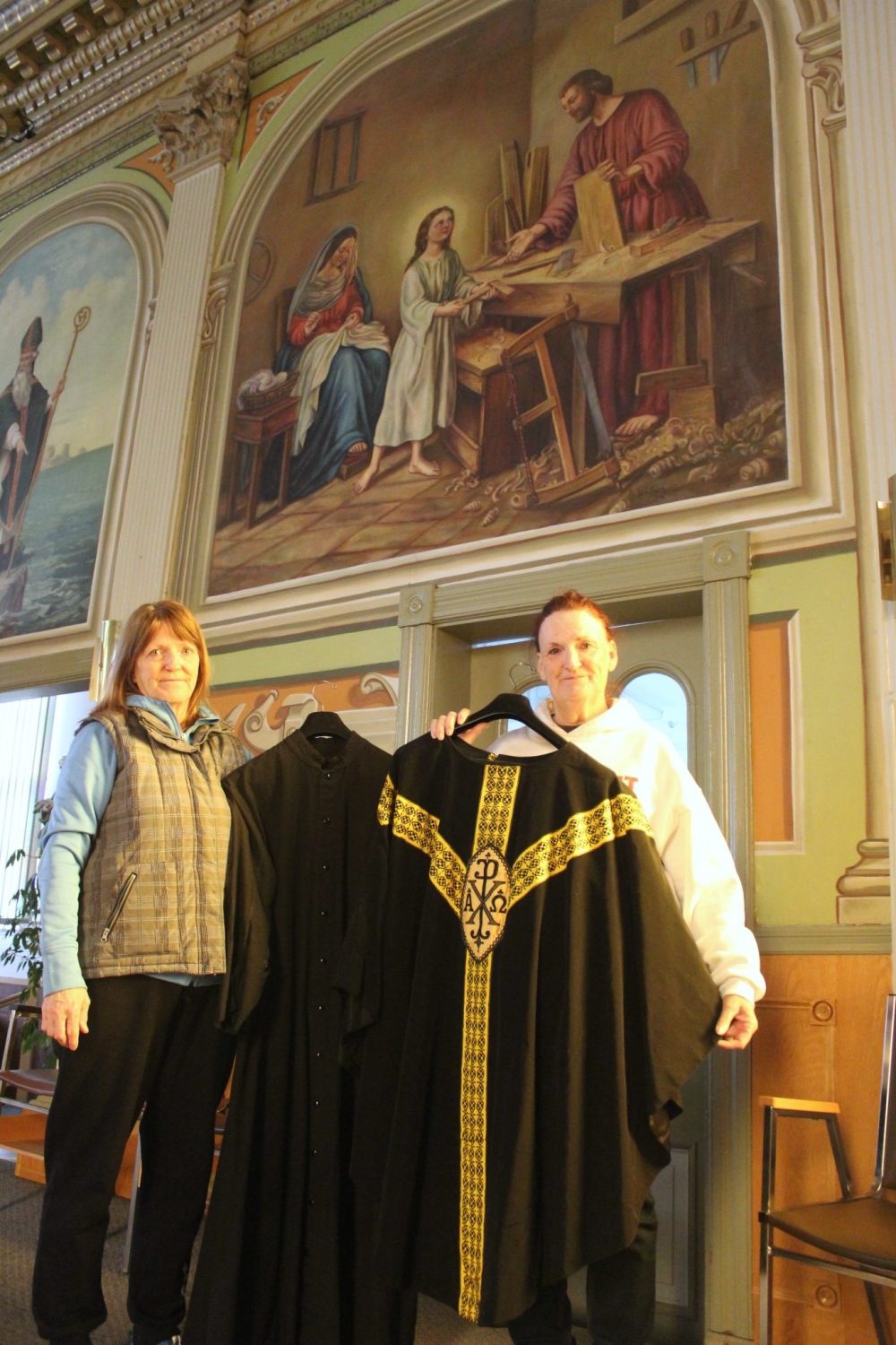 CHRIS GAREAU THE CARILLON
Lucille Brunette and her sister Colette Rozière with some antique vestments in front of one of the relatively newer paintings in Notre-Dame-de-Lorette by parishioner Noel Gauthier from 1948 depicting a young Jesus, Mary and Joseph.