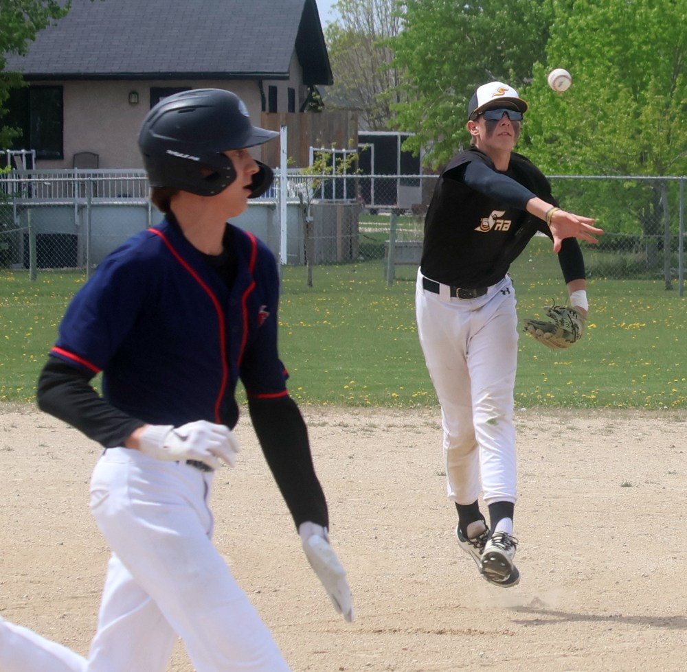 A Sabres player throws to beat out a St Joachim player at first base. (Cassidy Dankochik The Carillon)