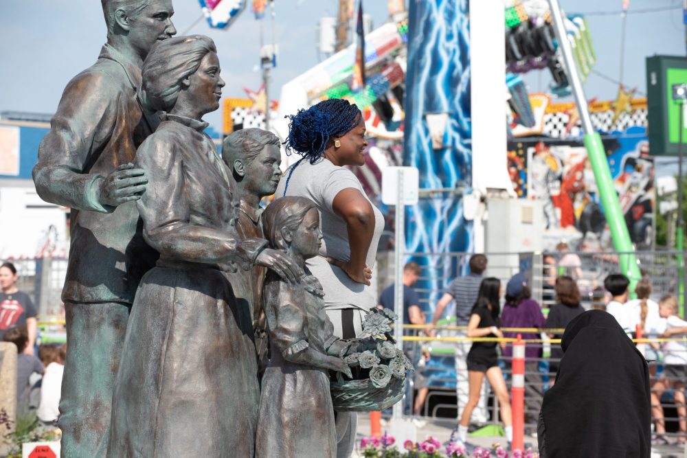 SVJETLANA MLINAREVIC THE CARILLON
Nigerian Omolade Onafalujo had fun posing with the Ukrainian statues at the clock tower at Summer in the City on June 13, 2025 in Steinbach.