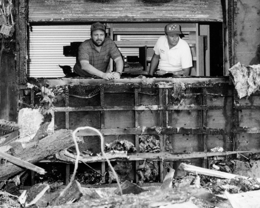 Deputy fire chief Bruce Streeter and Ste Anne fire chief Ken Dayment survey the rubble of the curling rink through the window from the arena concession area, which was undamaged in the fire. The steel panel covering the window separating the two buildings was red hot during the fire.