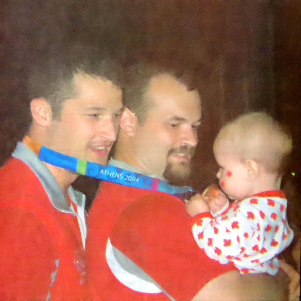 Joey Johnson, left, shares his gold medal with his brother, Bill, and six-month-old niece Hope after Canada defeated Australia in the gold-medal final at the 2004 Paralympic Games in Athens. (Carillon Archives)