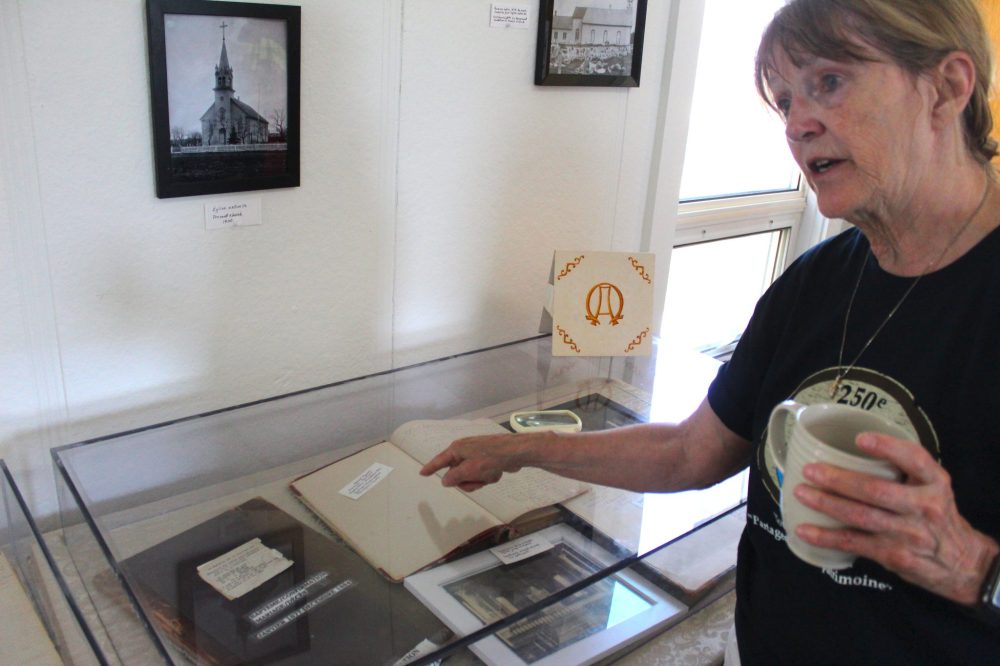 CHRIS GAREAU THE CARILLON
Parish committee member Lucille Brunette points to original baptismal and death records that date as far back as 1877. They were part of the display for the parish's anniversary events on June 21-22.