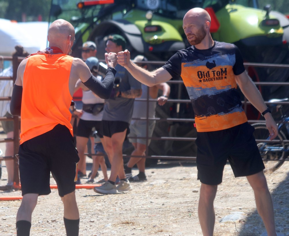 Race director Steffan Reimer fist bumps a competitor as he completes lap six of the Old Tom Backyard Ultramarathon. (Cassidy Dankochik the Carillon)