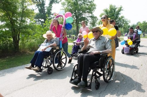 SVJETLANA MLINAREVIC THE CARILLON 

Villa Youville residents Eliette Marion and her daughter Yvette Desrochers (back) and Roger Bremault and volunteer Manon Jolicoeur (front) smile and wave as they make their way down the parade route in Ste Anne on July 24. Residents had fun with the 1950s theme at the annual scooter parade.