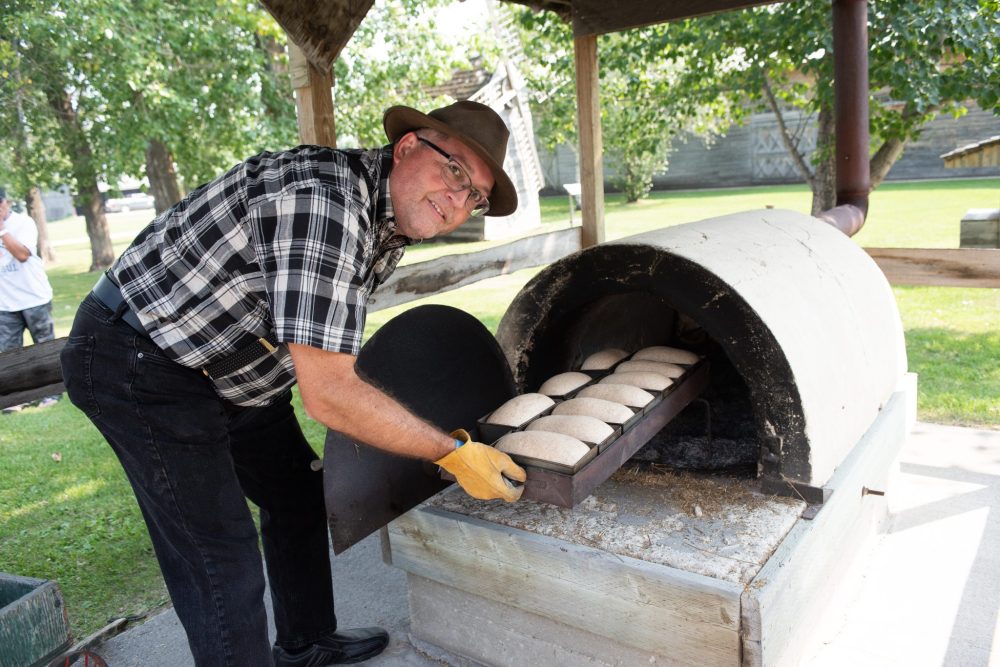 SVJETLANA MLINAREVIC THE CARILLON
Volunteer Francisco Fernandez puts fresh bread dough into the outdoor clay oven during the Mennonite Heritage Village's Pioneer Days on Aug. 2, 2025.