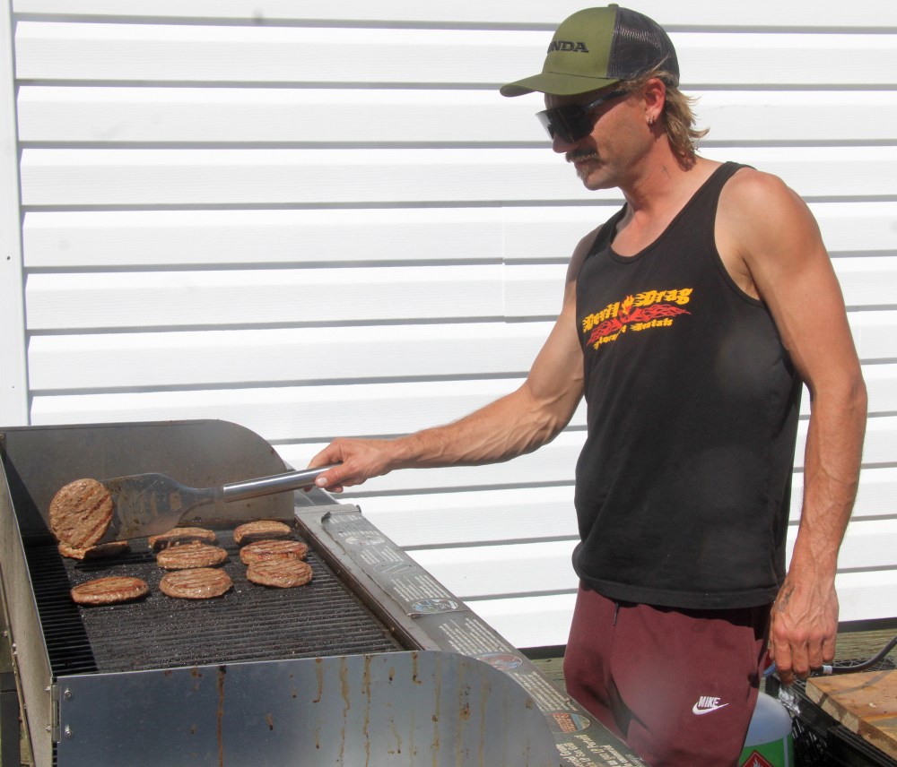 A canteen worker flips burgers at Marchand's Logging Days Aug. 24. (Cassidy Dankochik The Carillon)