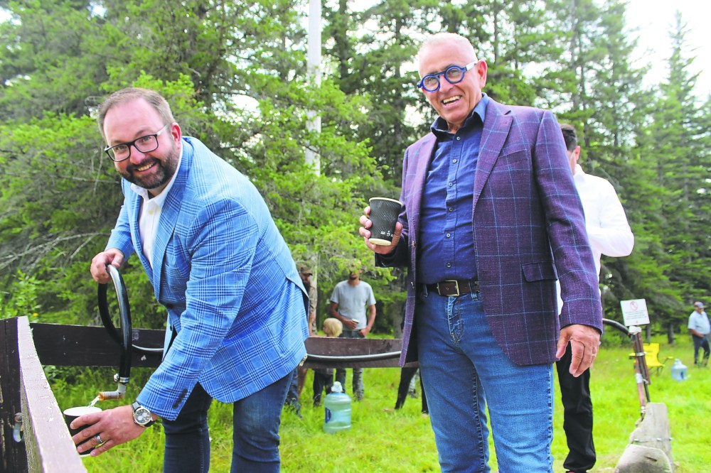 MATTHEW FRANK THE CARILLON Left, Progressive Conservative MLAs Konrad Narth and Jeff Bereza pour cups of water from the Piney semi-public water fill station, after it reopened on July 31.