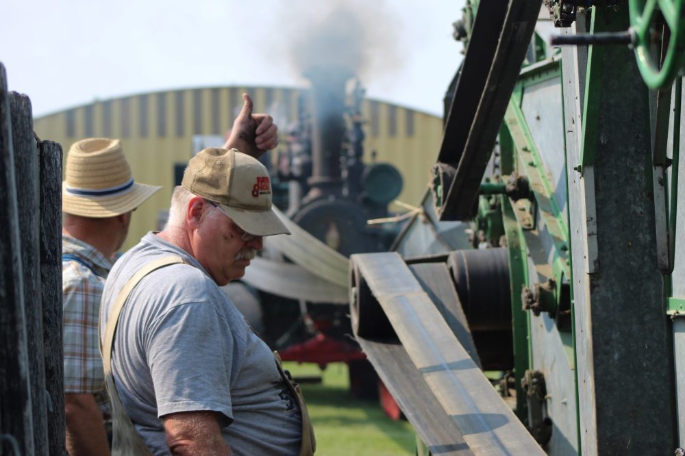 MATTHEW FRANK THE CARILLON
Conrad Peters puts his thumbs up after inspecting the belt connected to the threshing machine.