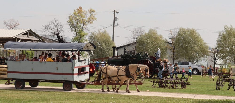 Volunteers and visitors have conversations about life in a pioneer village.
