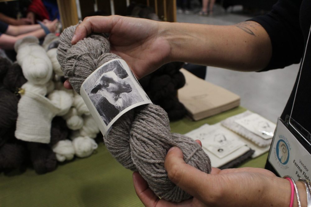 MATTHEW FRANK THE CARILLON
Christel Lanthier holds yarn made from her sheep. Each bundle of yarn has the picture and name from the sheep its from.